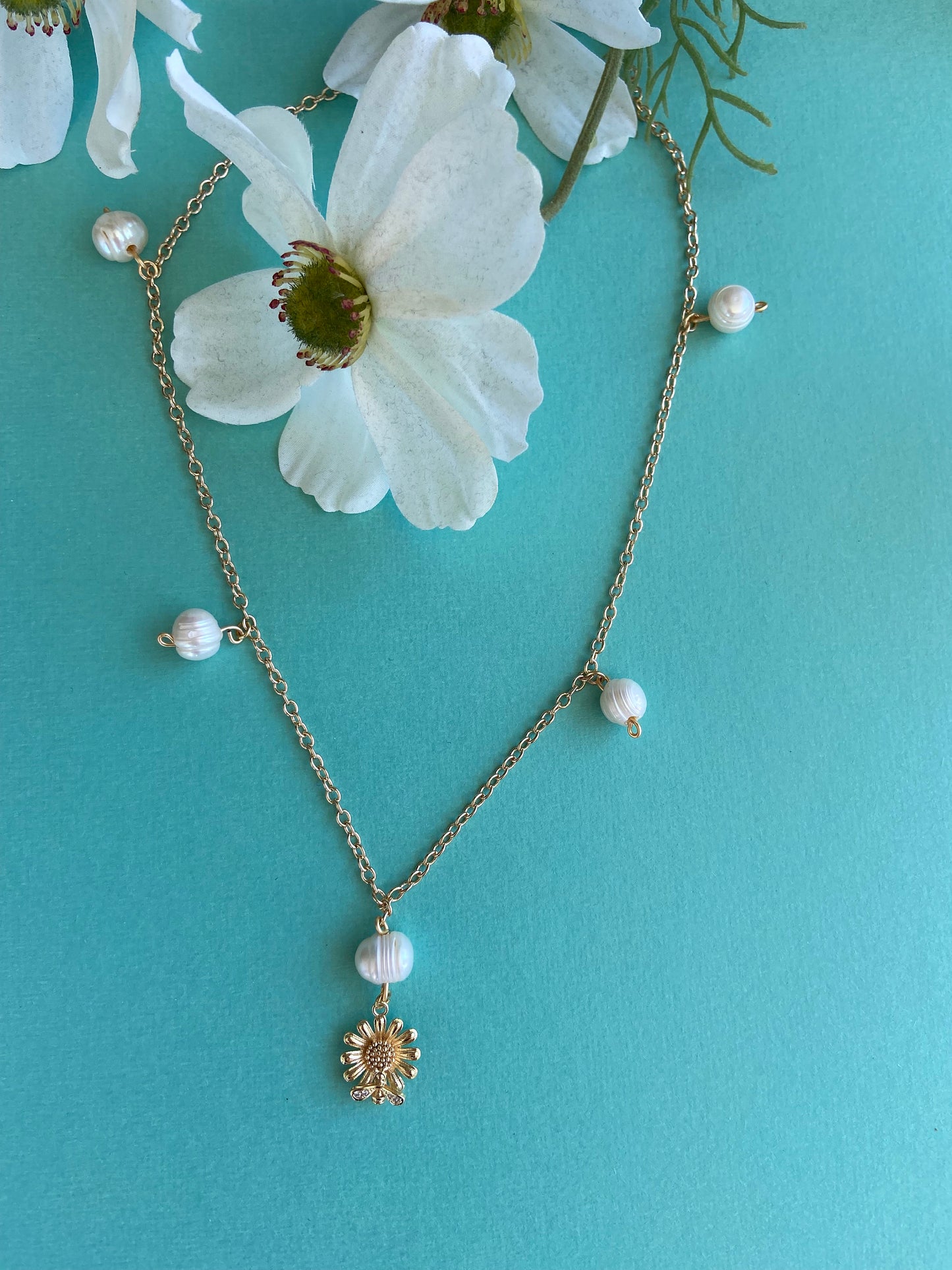 Dainty Gold daisy flower with bee pendant displayed on a gold chain with natural pearls on gold chain necklace.