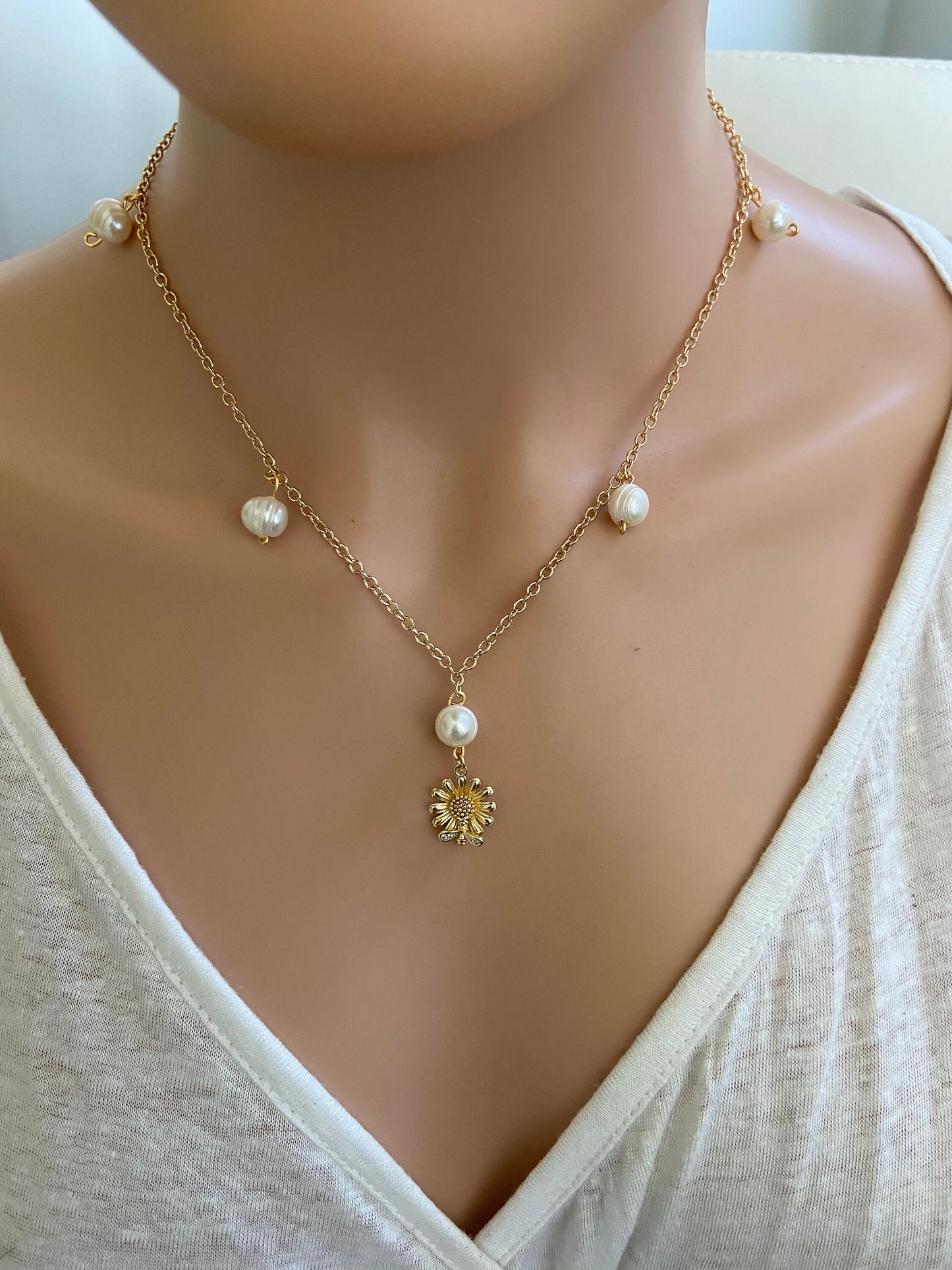Dainty Gold daisy flower with bee pendant displayed on a gold chain with natural pearls on gold chain necklace.