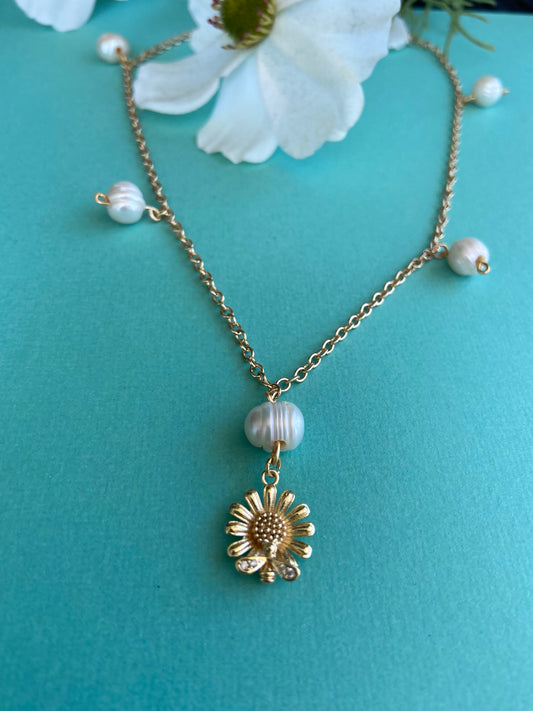 Dainty Gold daisy flower with bee pendant displayed on a gold chain with natural pearls on gold chain necklace.
